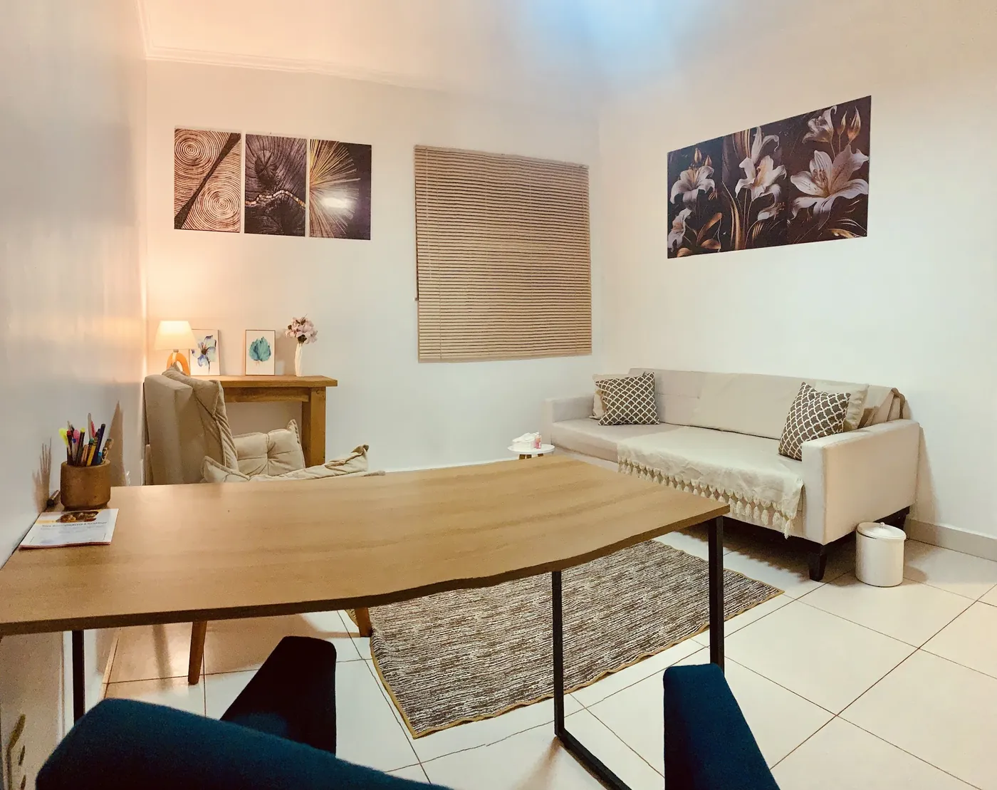 Sala de atendimento com mesa, sofá e quadros